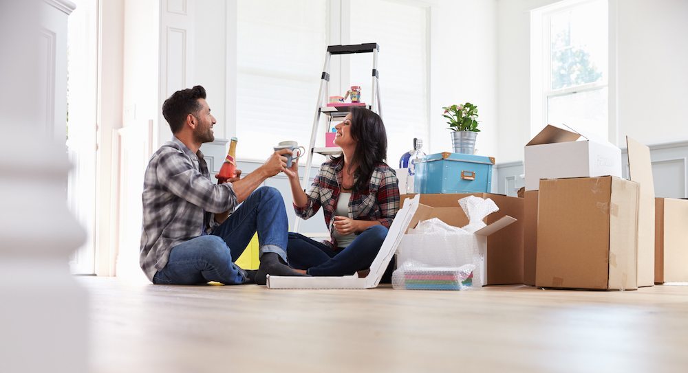 Moving Day Tips | Couple enjoying pizza and beer on the floor of their empty new apartment